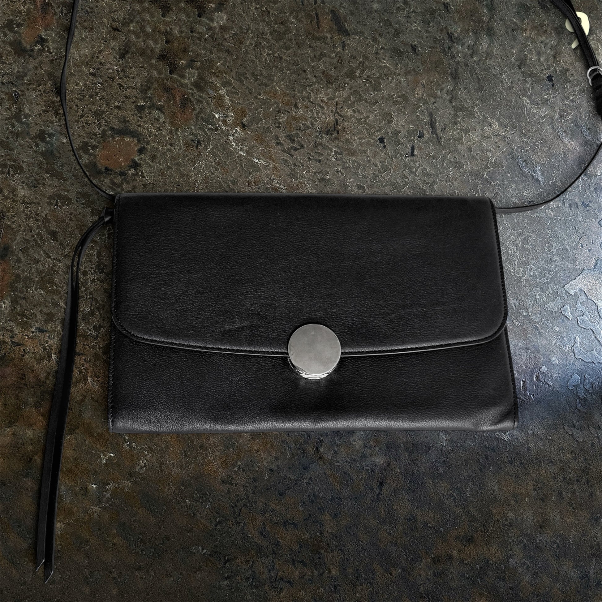 Ann Demeulemeester black leather shoulder bag front view with branded silver closure