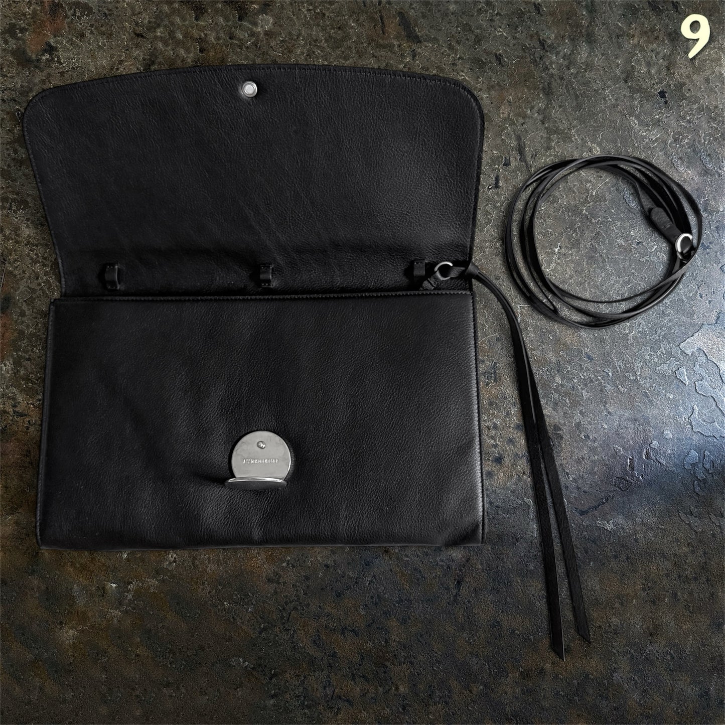 Open Ann Demeulemeester black leather bag showing interior and coiled adjustable strap