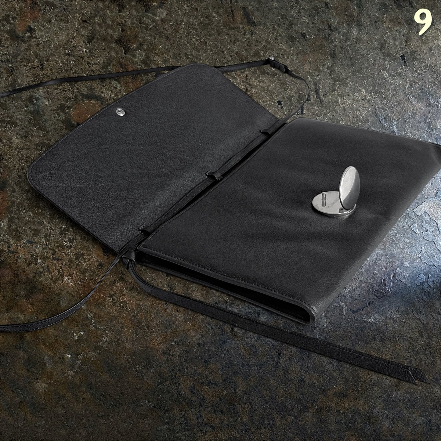 Ann Demeulemeester black leather bag open at an angle showing silver metal closure